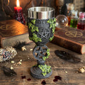 Decorative goblet with pentacle design on a wooden surface with books and candles.