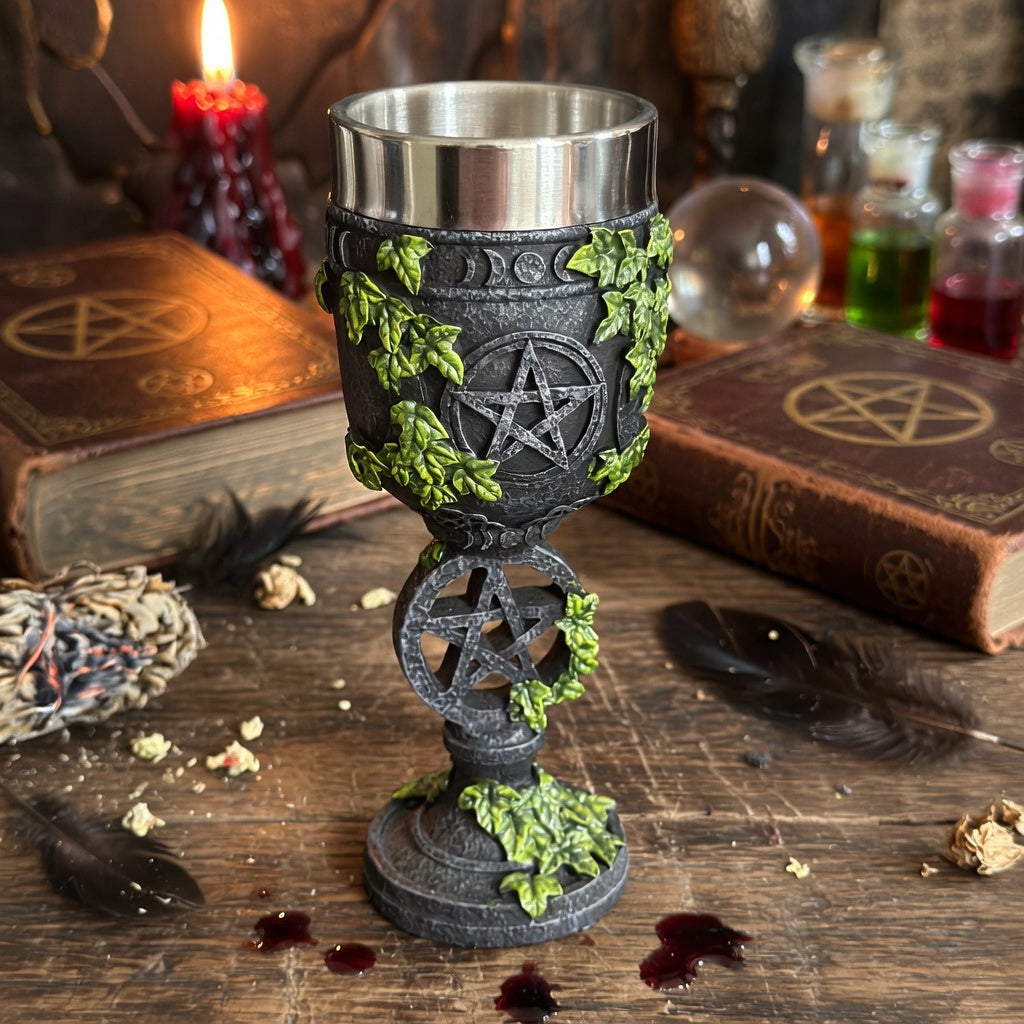 Decorative goblet with pentacle design on a wooden surface with books and candles.