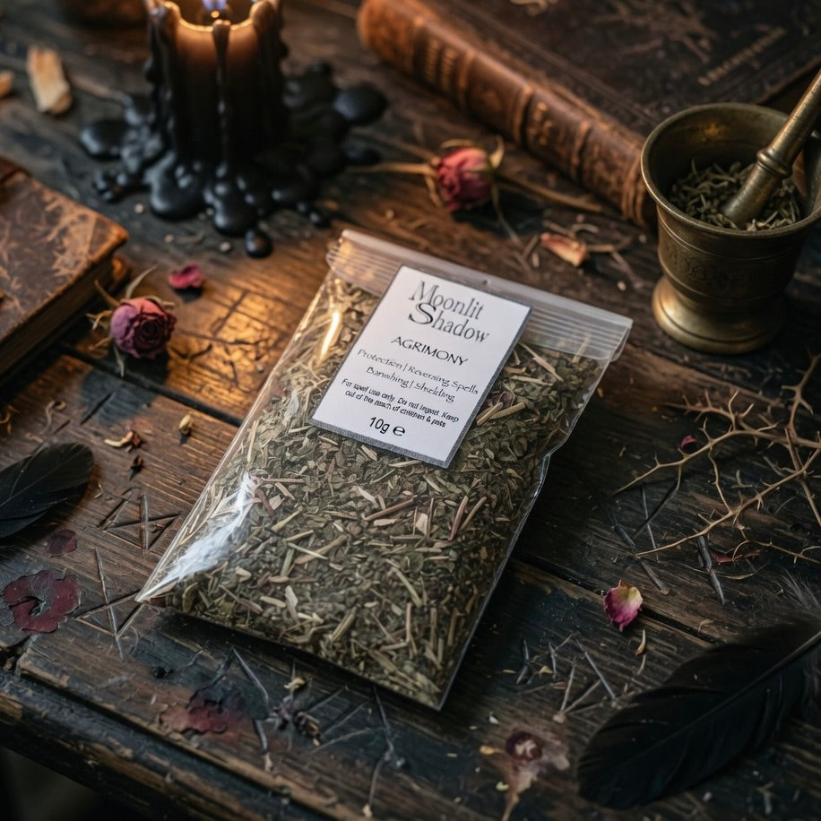 Package of dried agrimony herbs labeled 'Moonlit Shadow' on a wooden surface with candles and books.