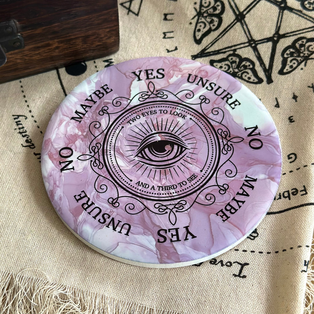 All seeing eye pendulum board on a cream cloth background