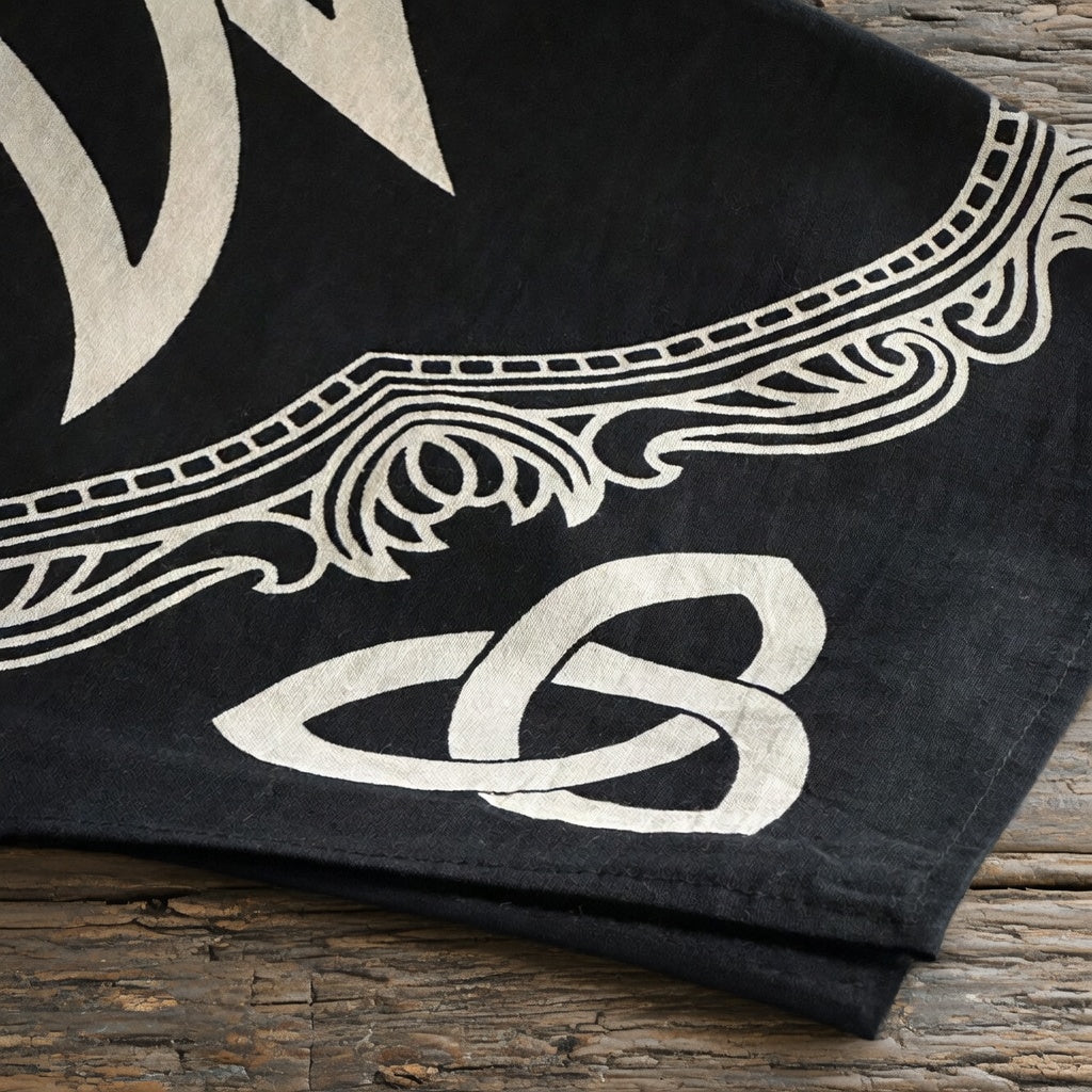 Black fabric with white Celtic knot design on a wooden surface