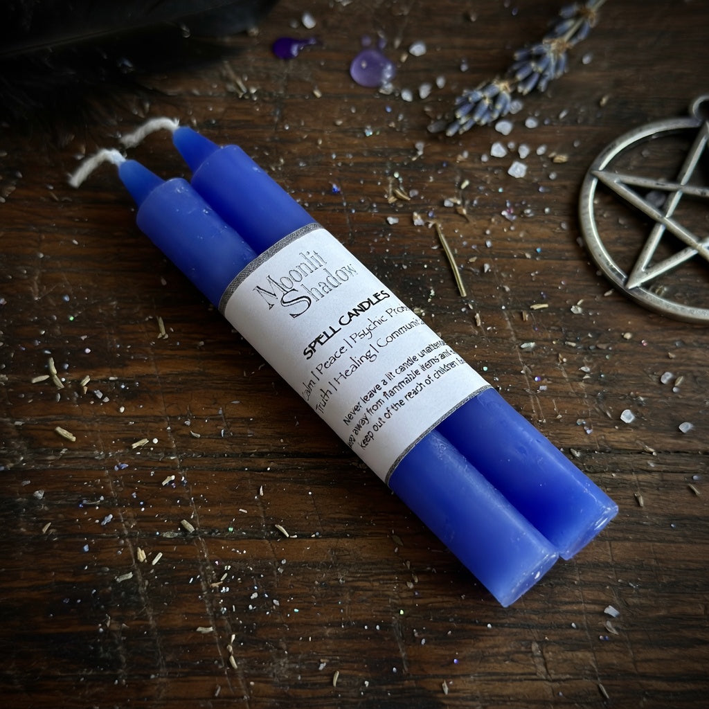 Blue spell candles with a label on a wooden surface with lavender and pentacle symbol.