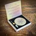 Dowsing pendulum set with instructions on a wooden surface with runes.