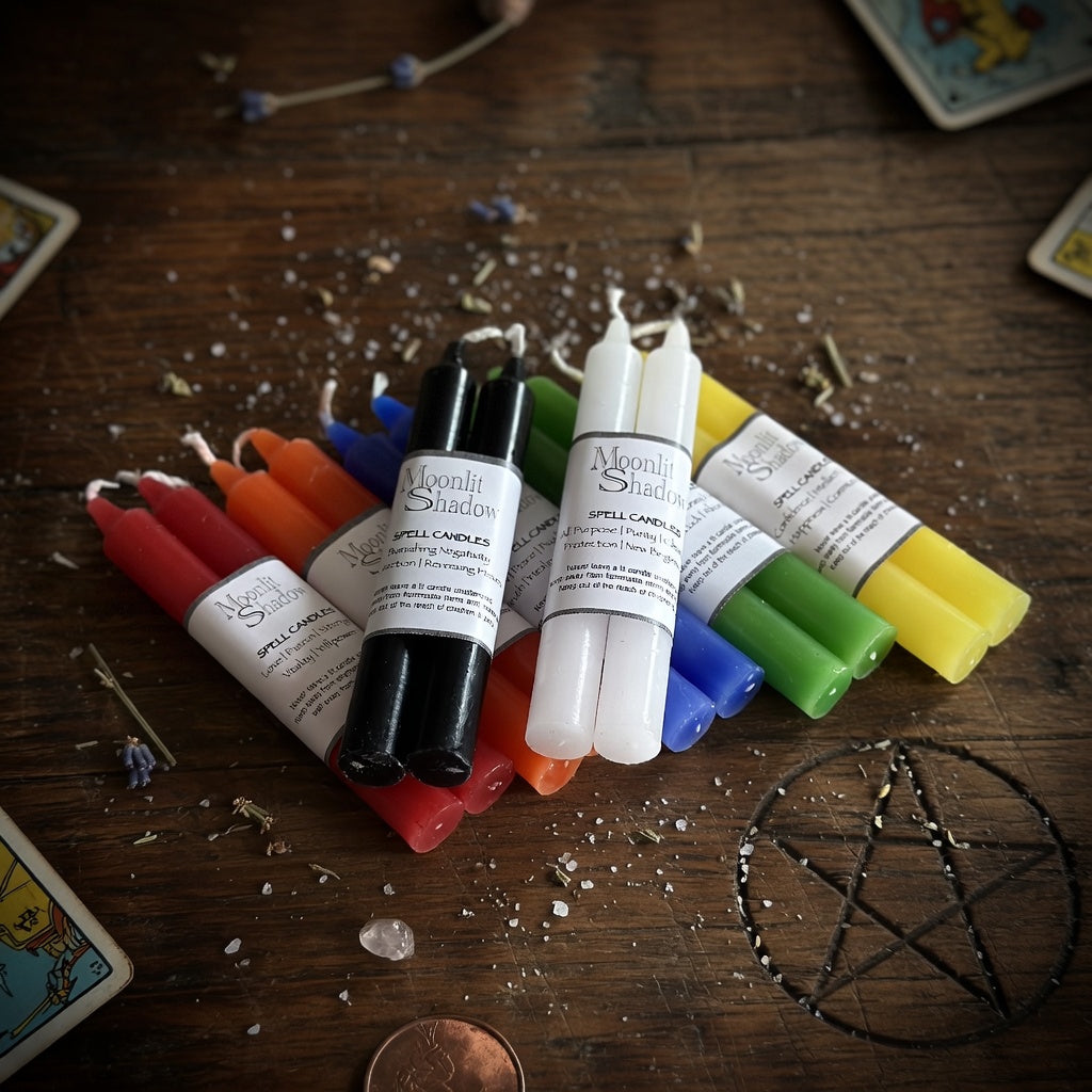 Colourful spell candles on a wooden surface with tarot cards and pentacle symbol.
