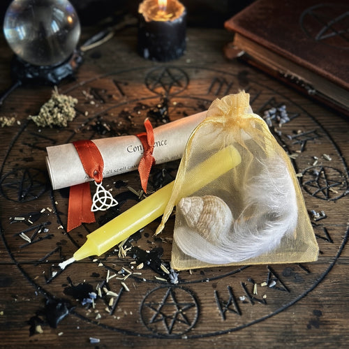 Confidence spell kit with scroll and candle on an occult themed carved wood surface
