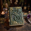 Dragons grimoire journal in green resin, on a wooden surface with candle and crystal ball.