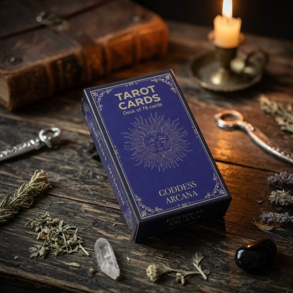 Tarot card deck with 'Goddess Arcana' on a wooden surface with herbs and a candle.