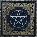 Black fringed altar cloth with gold celtic knot design border and white pentagram, on a wooden surface