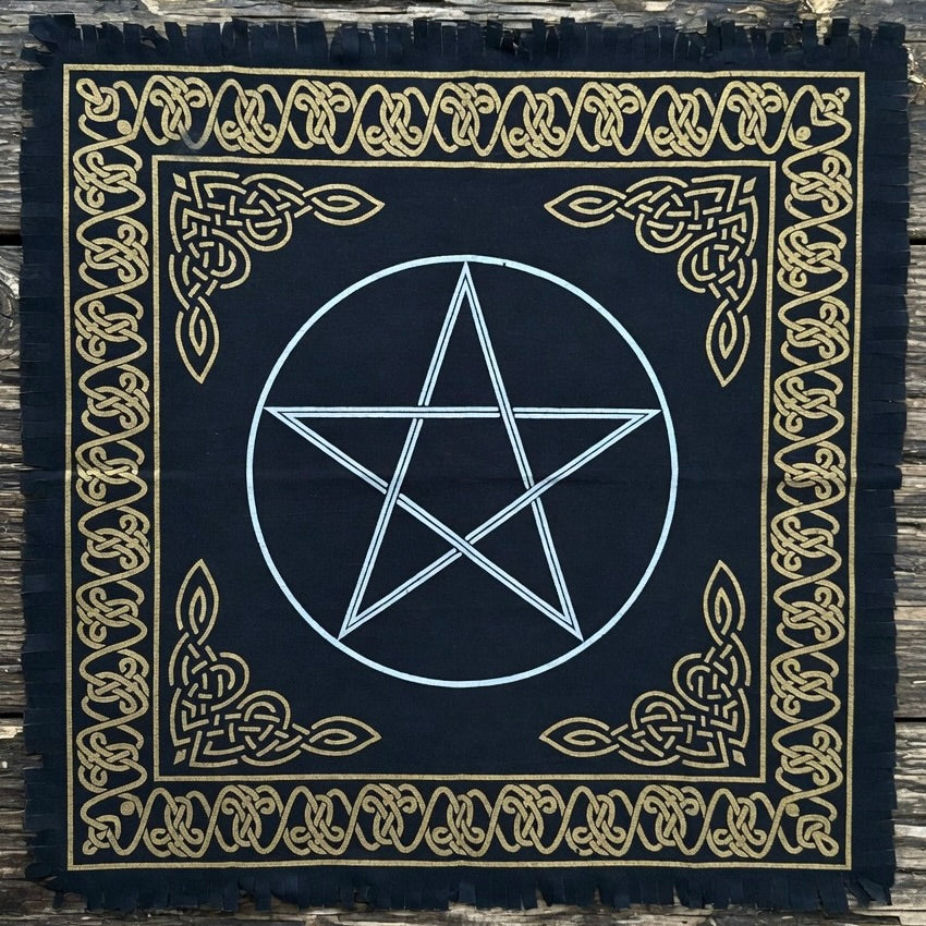 Black fringed altar cloth with gold celtic knot design border and white pentagram, on a wooden surface