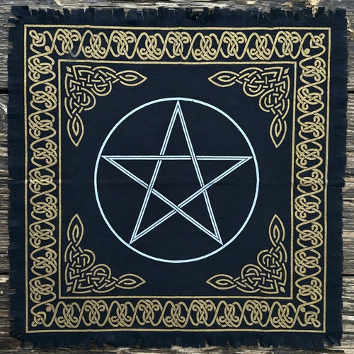 Black fringed altar cloth with gold celtic knot design border and white pentagram, on a wooden surface