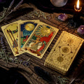 Golden tarot cards on a wooden surface with herbs, a crystal ball, and a candle.