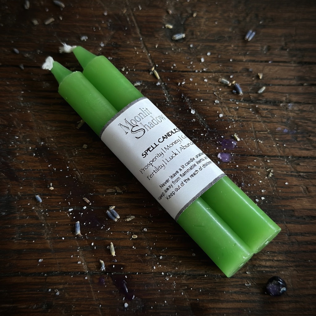 Green spell candles with a label on a wooden surface