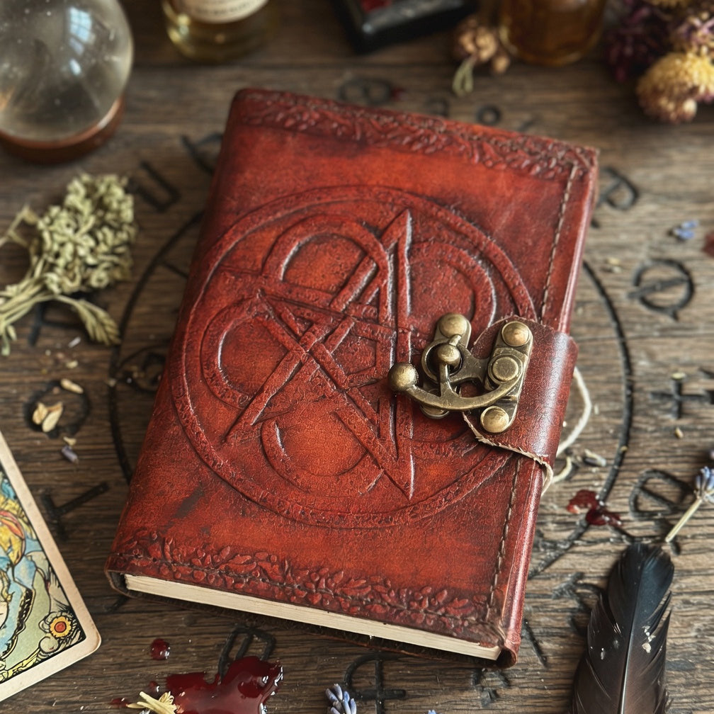 Brown leather book of shadows with embossed pentagram design and lock on a wooden surface with tarot cards and herbs.