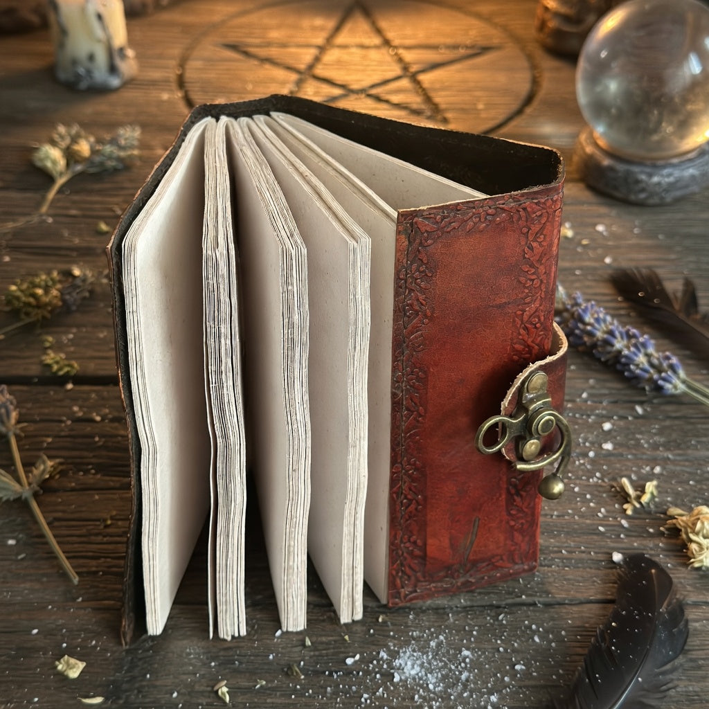 Leather-bound book of shadows on a wooden surface with mystical symbols and objects.