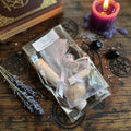 Moonlit Shadow Letting go and forgetting spell kit on a wooden surface with sprinkling of herbs and pagan Carving