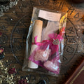 Moonlit Shadow love spell kit with scroll and candle on rough wooden surface with occult symbols