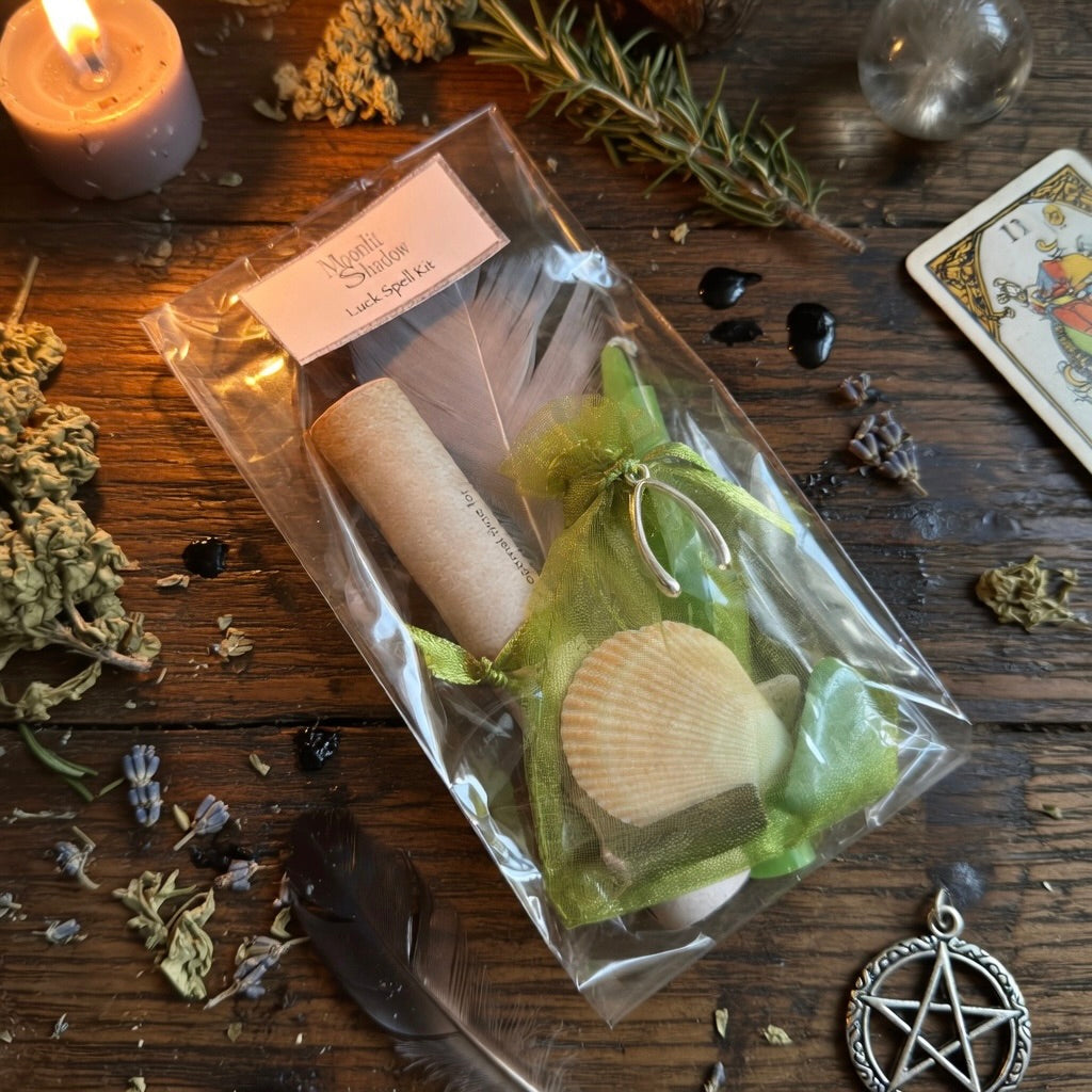 Moonlit Shadow luck spell kit on a wooden surface with sprinkling of herbs and a lit candle