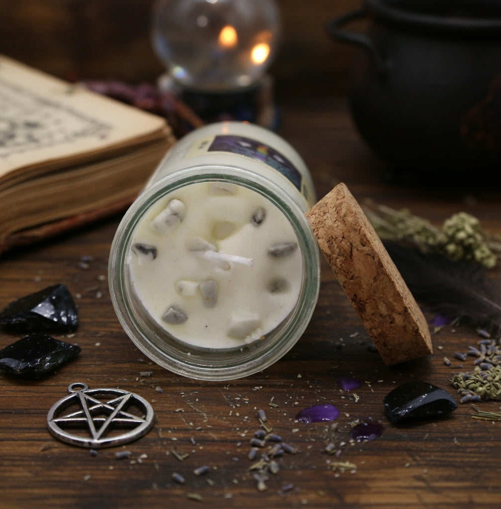 Spell candle in a glass jar on a wooden surface with mystical items around