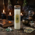 Happiness spell candle in a glass jar with a label on a wooden surface with candles, cards, and other occult items.