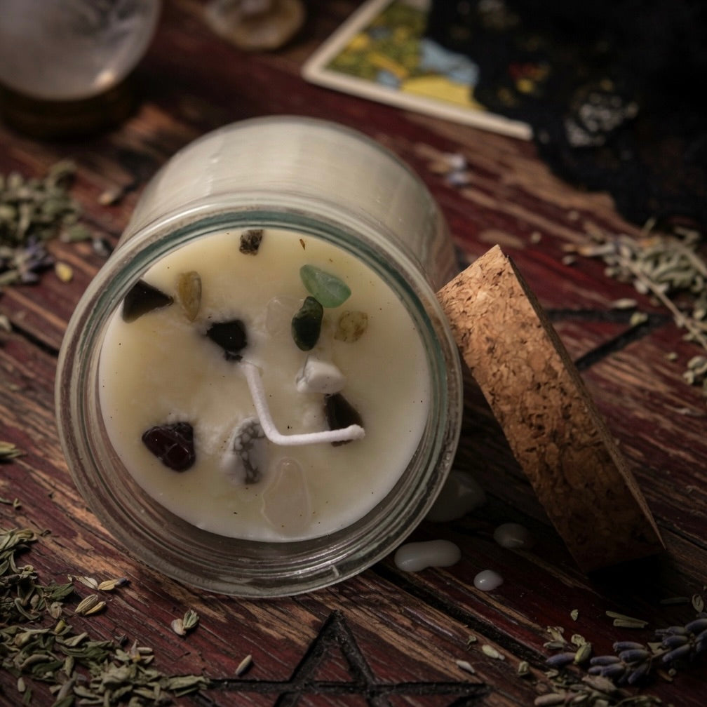 Seduction spell candle in a glass jar with decorative elements on a wooden surface with herbs and a tarot card.