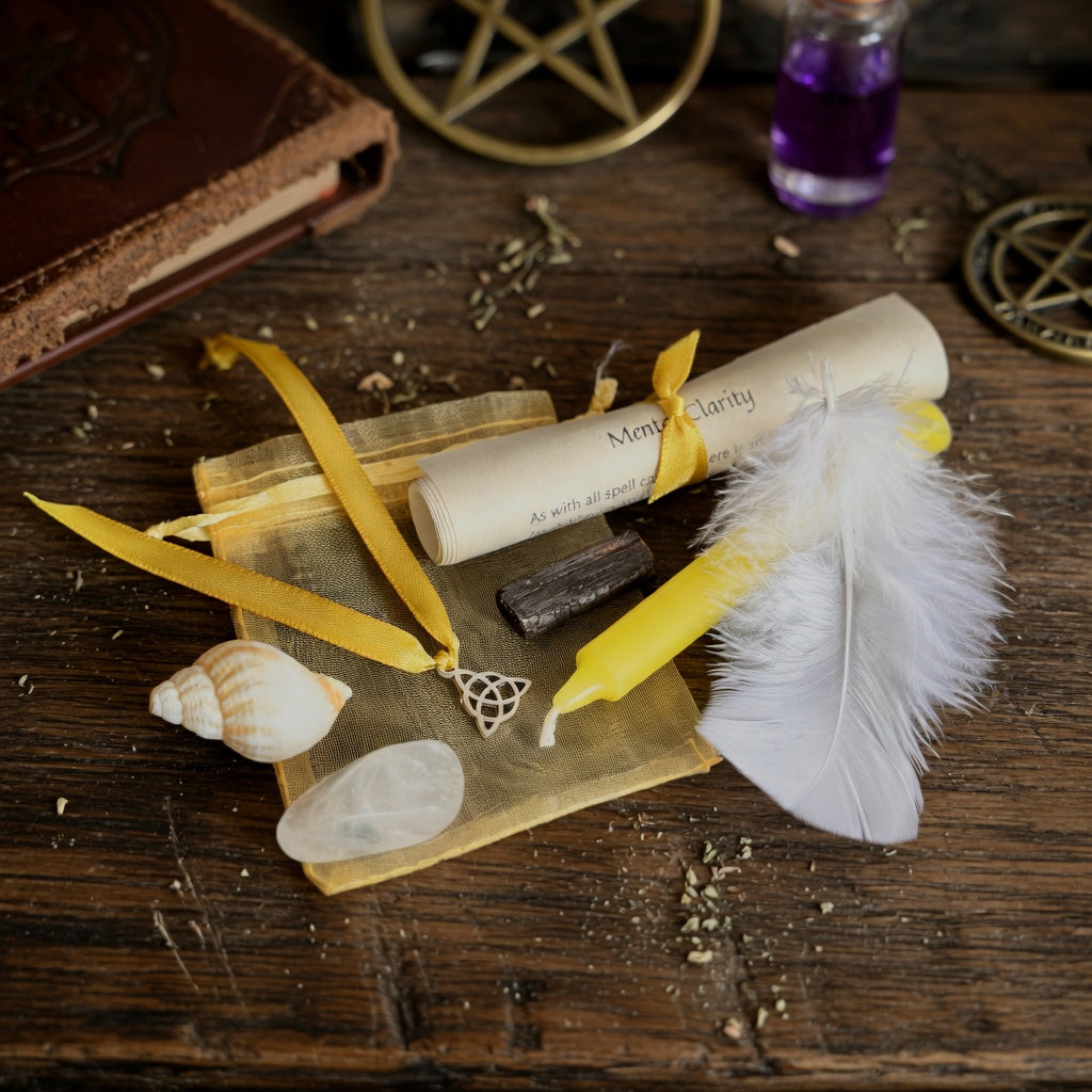 Mental clarity spell kit with scroll, feather, candle and shell on a dark wood surface with occult witchcraft items