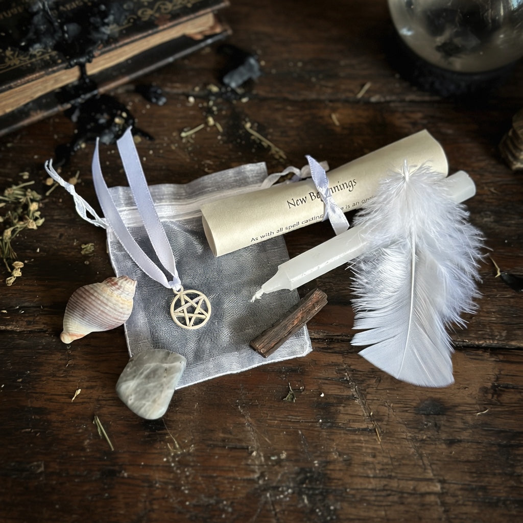 New beginnings spell kit with scroll, feather, shell and candle on a rough dark wood surface with occult items