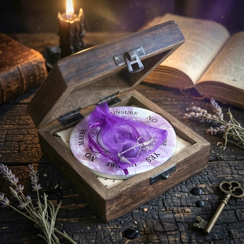 Pendulum divination gift set with cloth, pendulum board, carved wooden box and amethyst pendulum on a rustic wooden table with candle, book and key