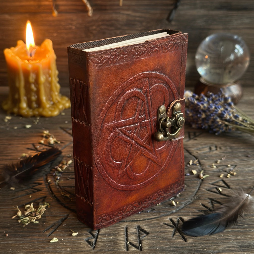 Brown leather book with pentagram design on a wooden surface with candles and crystals.