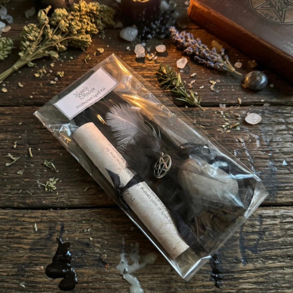 Moonlit Shadow Protection spell kit on a wooden surface, with a sprinkling of herbs and a book