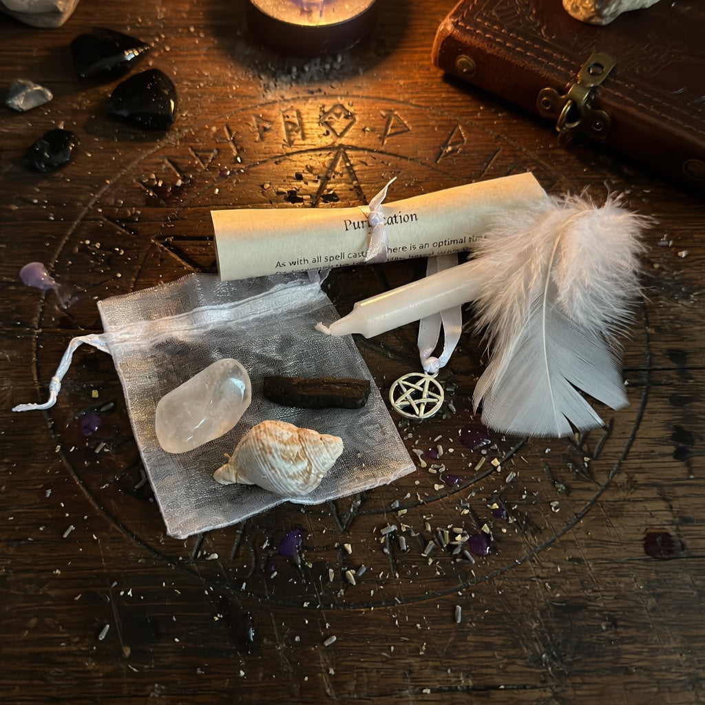 Purification spell kit, including a pentacle, feather, crystal, and candle on a wooden surface with witchcraft symbols.