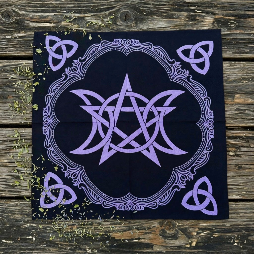 Black altar cloth with purple pentagram and triple moon design on a wooden surface