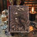 Decorative resin journal with embossed design of a raven on a wooden surface with candles and books.