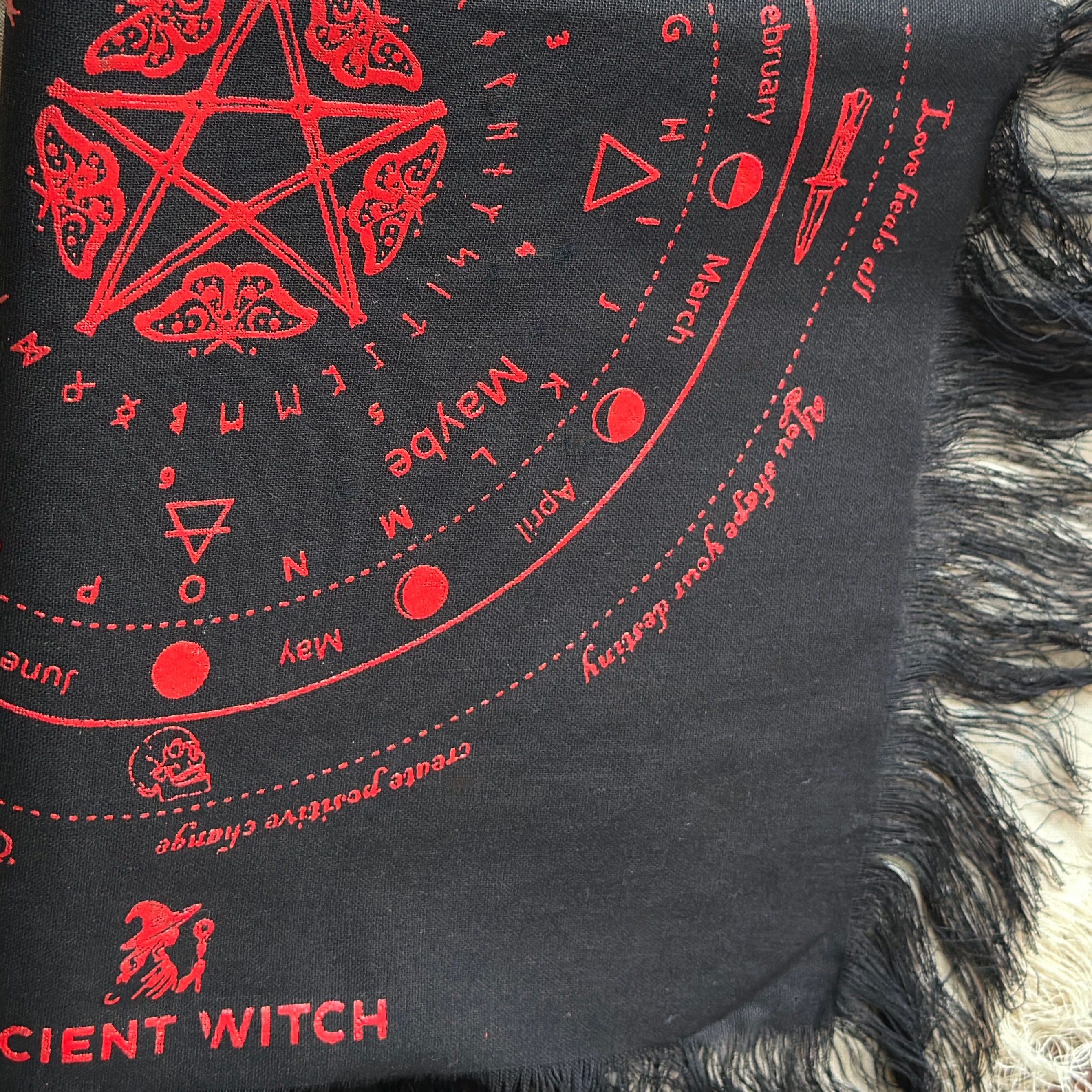 Black divination cloth with red witch-themed designs and text, including a pentagram and calendar symbols.