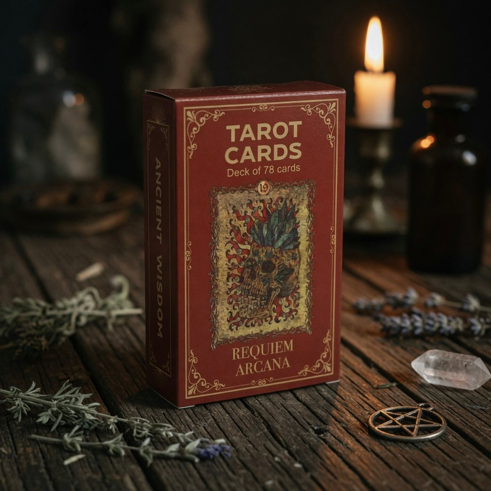 Requiem arcana tarot card box on a wooden surface with candles and herbs in the background