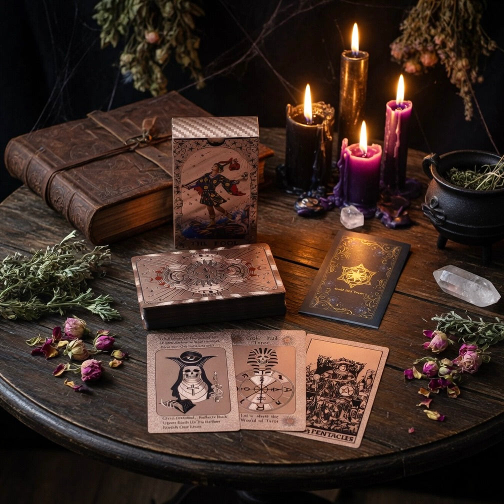 Rose gold tarot cards and guide, with candles, and herbs on a wooden table.