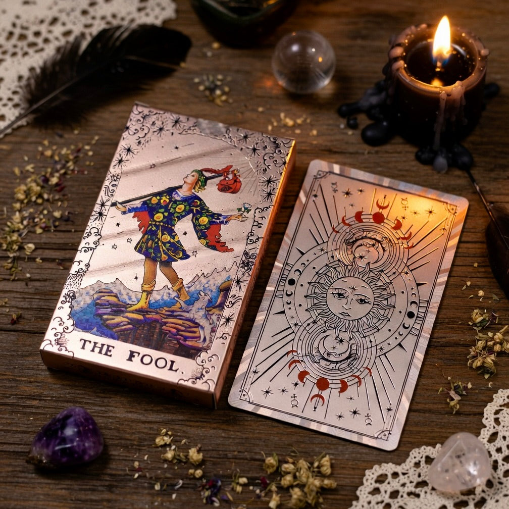 Rose Gold Tarot deck on wooden surface with herb sprinkles, a lit candle and crystal sphere