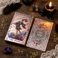 Rose Gold Tarot deck on wooden surface with herb sprinkles, a lit candle and crystal sphere