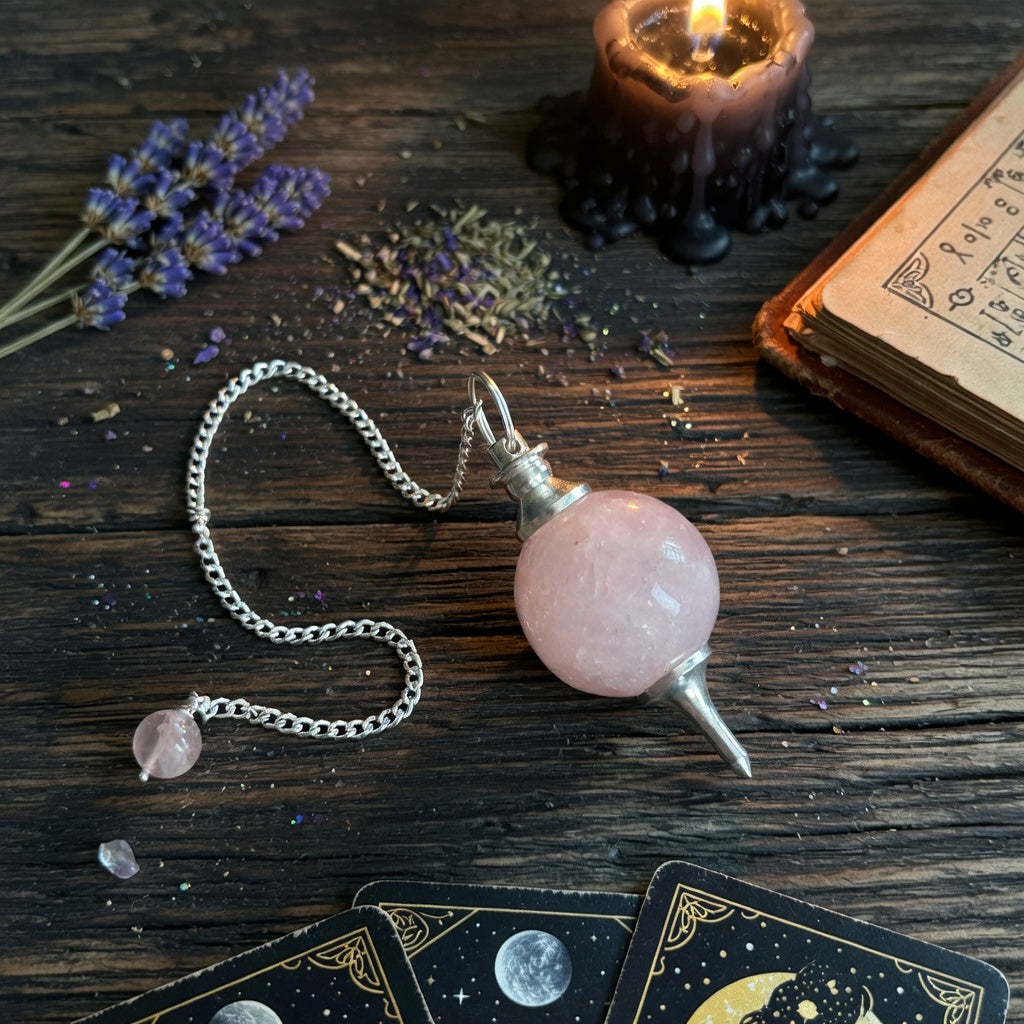 Rose quartz pendulum with chain on a wooden surface with lavender and candles