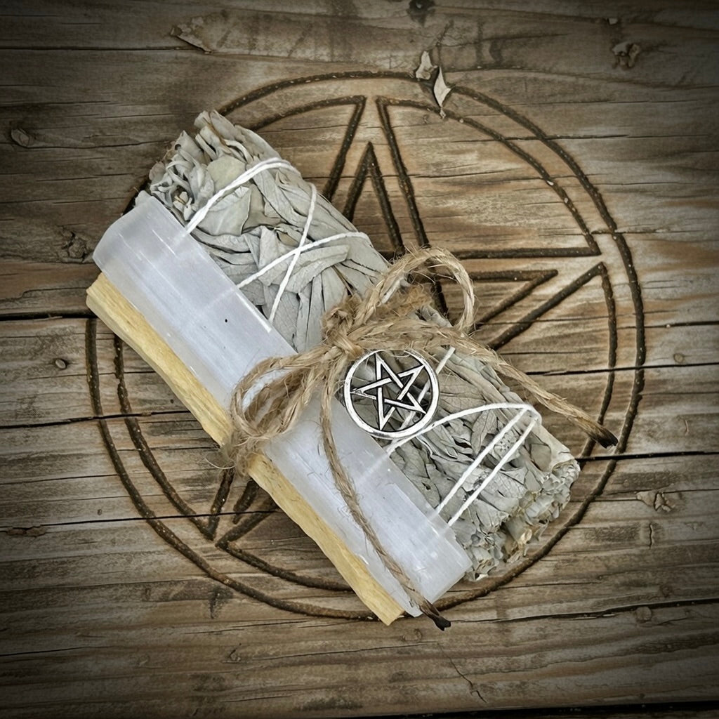 Bundled selenite, sage and palo santo sticks with a pentagram on a wooden surface.