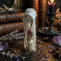 Self love witch charm bottle with heart charm, on a wooden surface with herbs, books and a lit candle