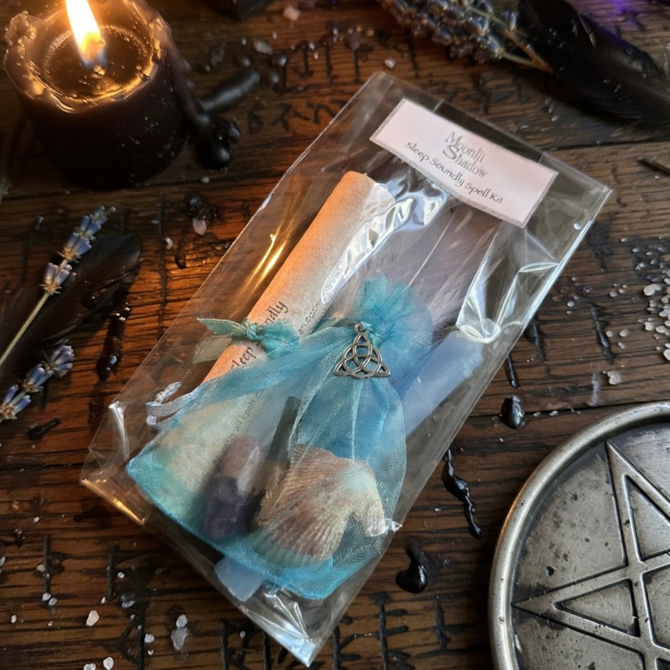 Sleep soundly spell kit with scroll and blue candle, on a wooden surface with occult carvings, herb sprinkles and witchcraft related items