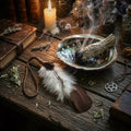 Brown smudging feather with incense, books, and candles on a wooden surface