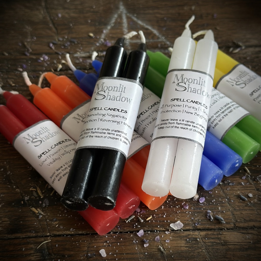 Colorful spell candles with labels on a wooden surface