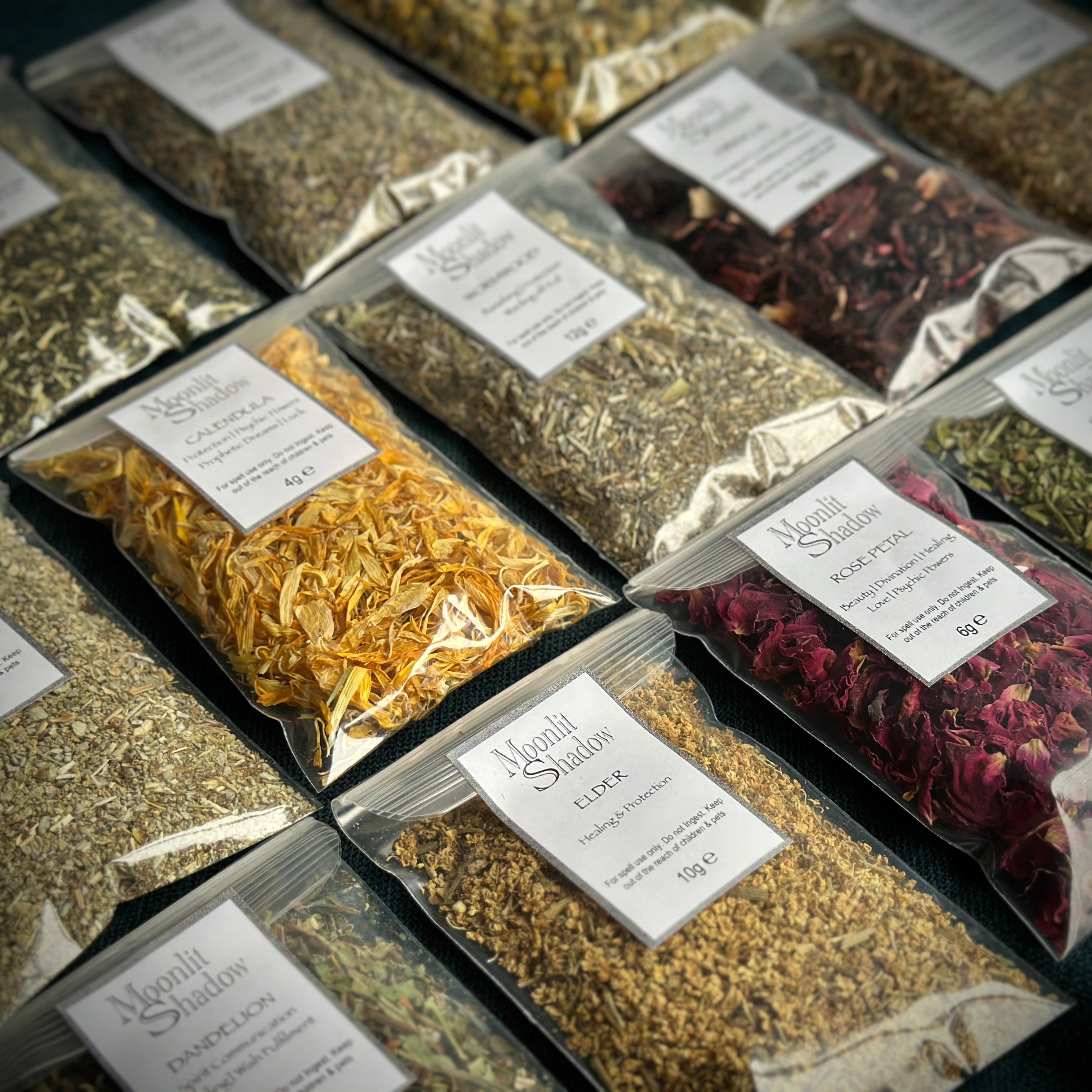A selection of spell casting herbs in labelled sachets, close up. Mugwort, calendula, yarrow