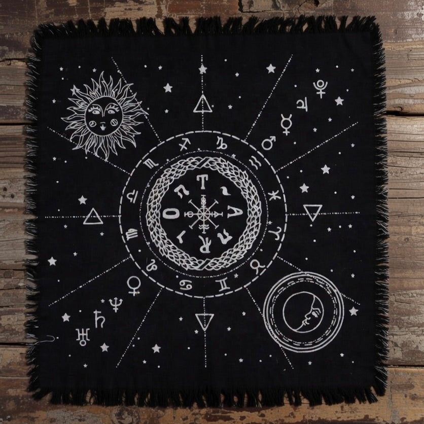 Black fringed altar cloth with white celestial designs on a wooden surface
