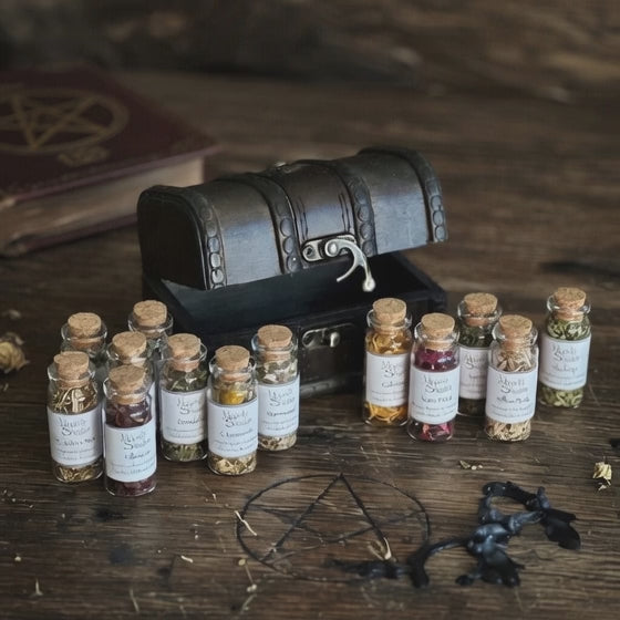 Spell herb gift bottles and wooden chest, on a carved wooden surface with book behind