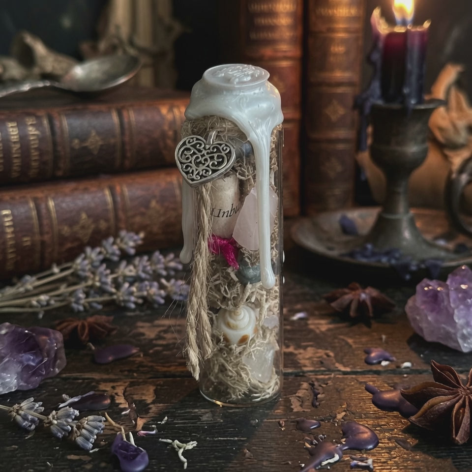 Self love charm bottle on a wooden background with books, crystals, herbs and a candle